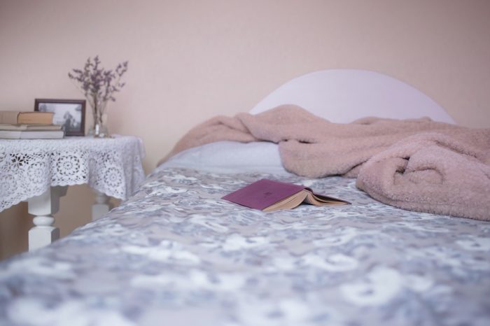 Cozy bed with a blanket and a book.