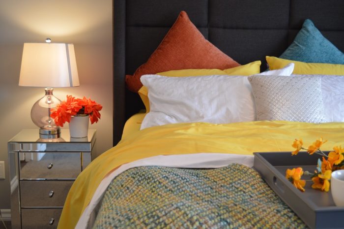 A cozy bed with a yellow and blue comforter.