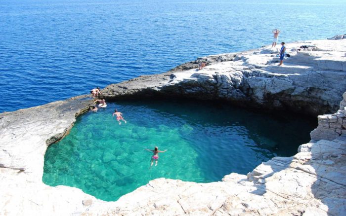 A group of people are swimming in a natural pool.