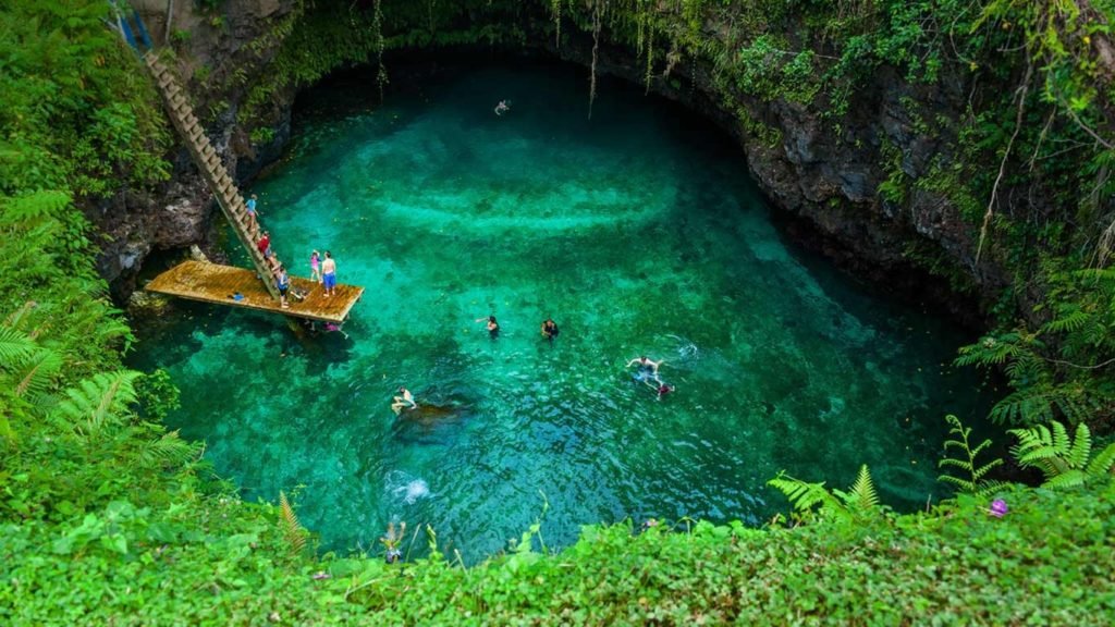 A group of people are swimming in natural pools inside a cave.