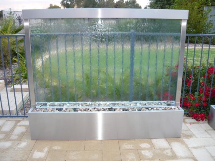 A stainless steel water fountain in a backyard that creates a relaxing atmosphere for your yoga room.