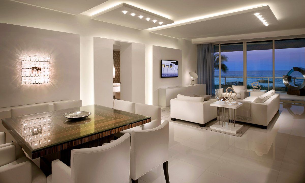 A modern living room with white furniture and LED lights.