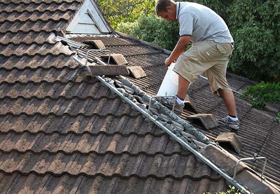 A man performing maintenance jobs on the roof of a house.