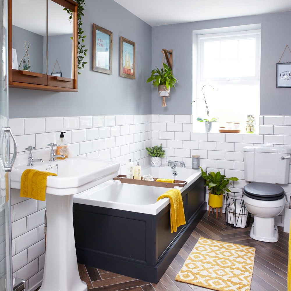 A bathroom with a tub, sink, and a yellow rug undergoing remodeling.