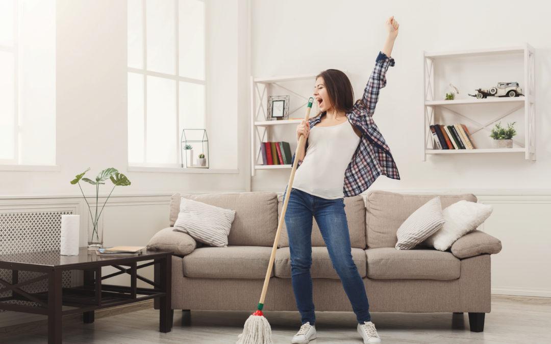 A woman creating a feel-good atmosphere by cleaning her living room with a broom.