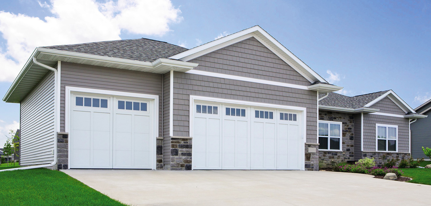A house with two garage doors and a grassy yard.