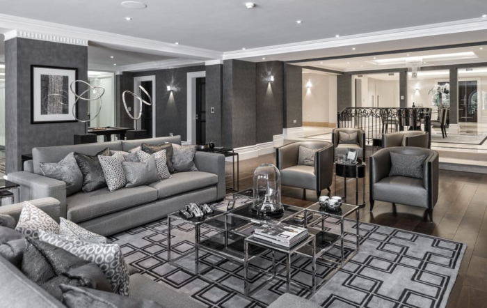 A modern living room with grey furniture and a glass coffee table.