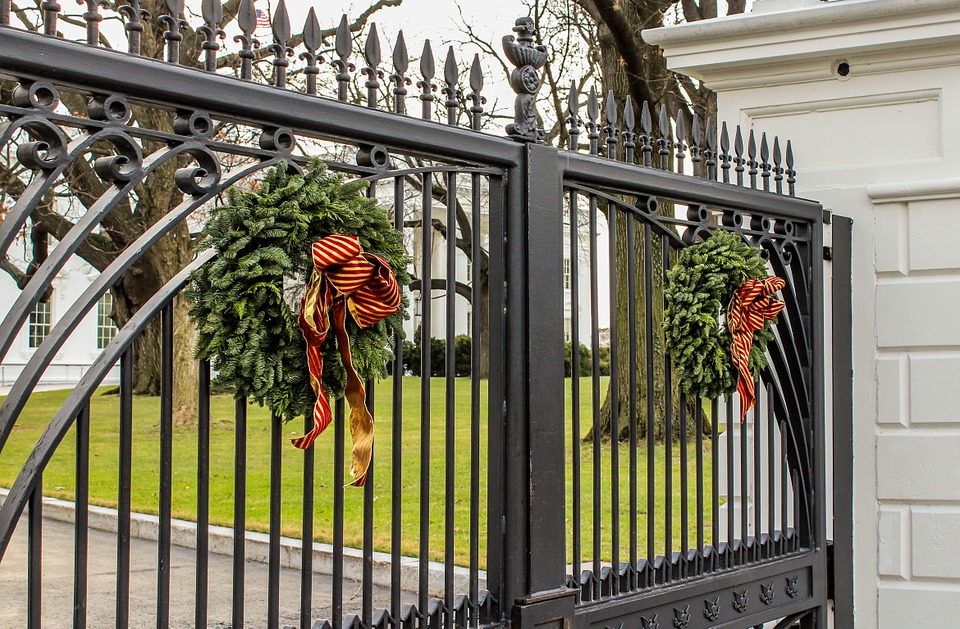 A gate design featuring wreaths on a white house gate.