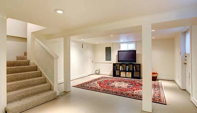A living room with a rug and stairs on the basement floor.