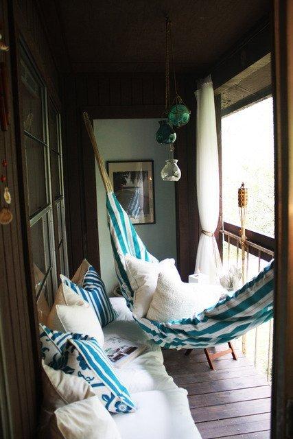 A hammock and pillows providing a comfortable nap corner on a porch.