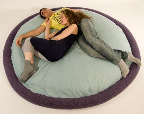 A couple napping on a round bed.
