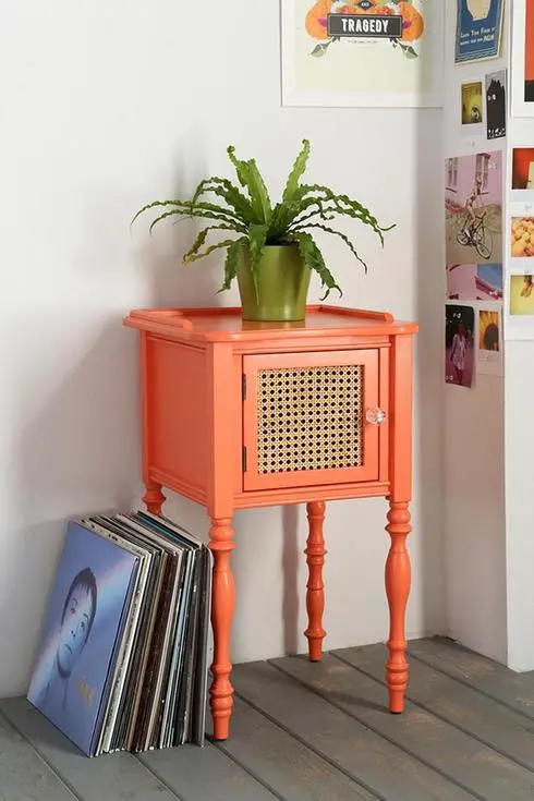 A vintage nightstand with a plant on top.