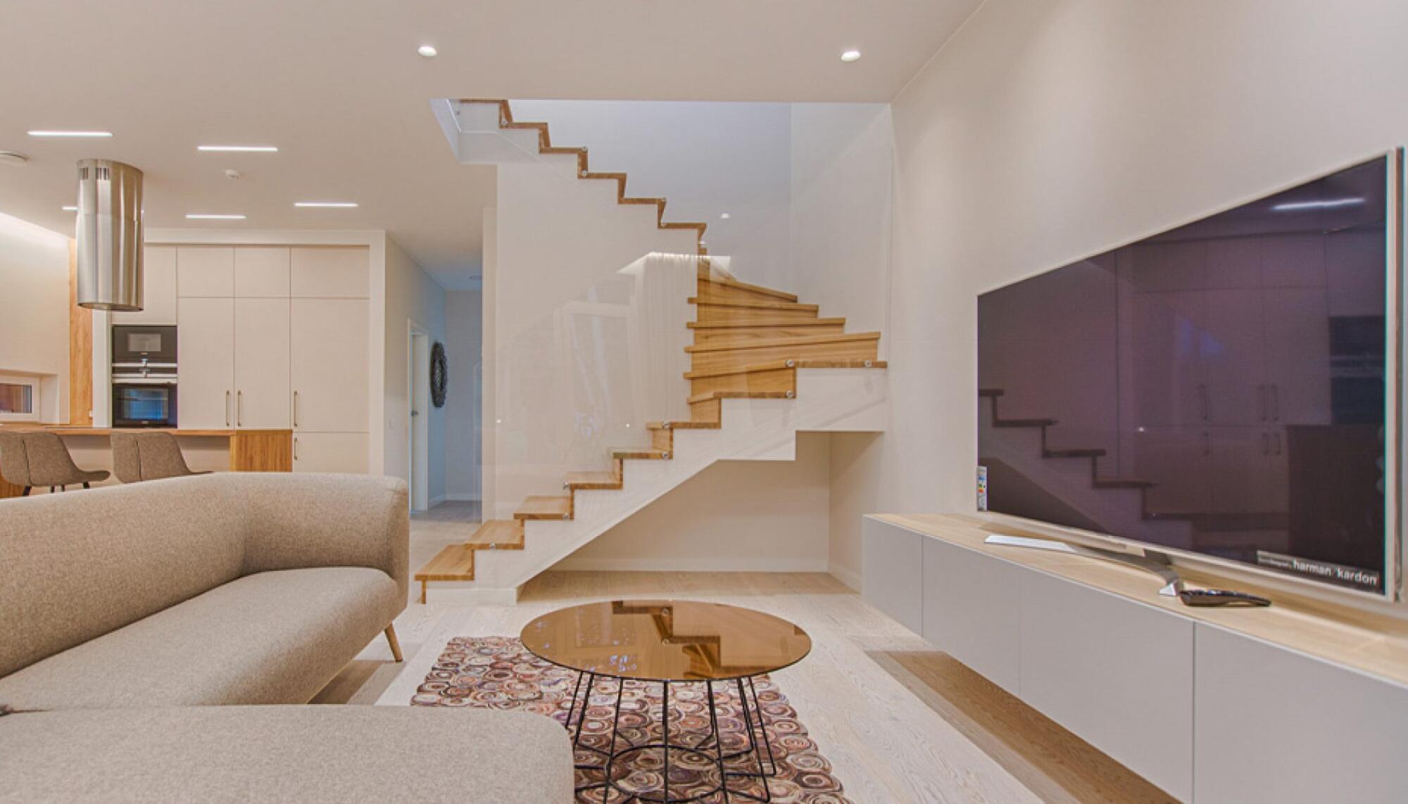 A modern living room with stairs and a TV in a finished basement.