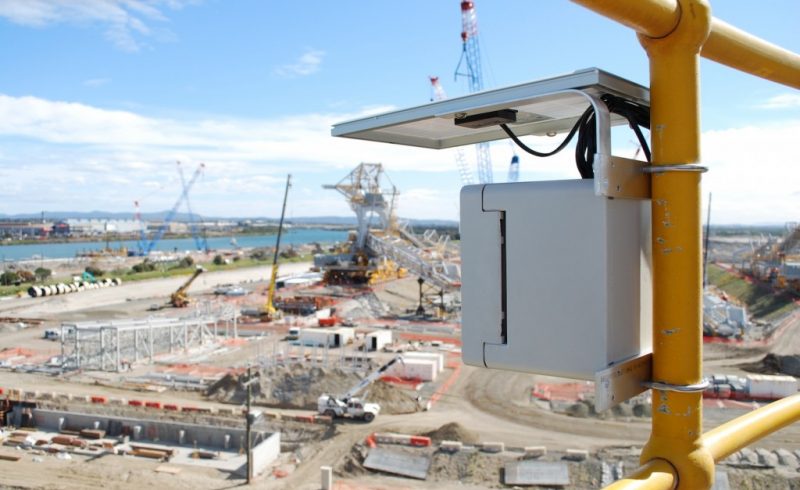 A construction camera is mounted on a pole near a construction site.