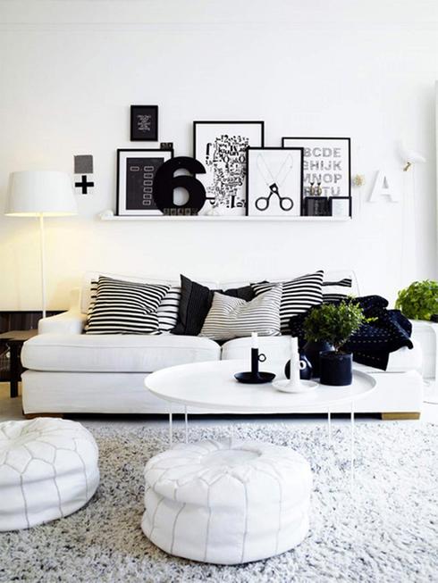 A white living room decorated with black and white photo frames.