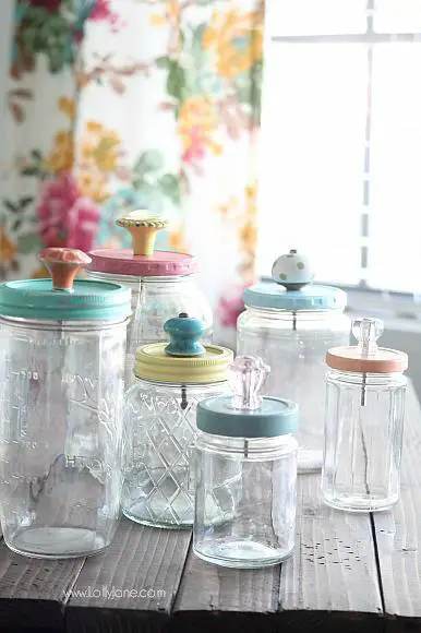 Vintage glass jars with colorful lids on a wooden table.