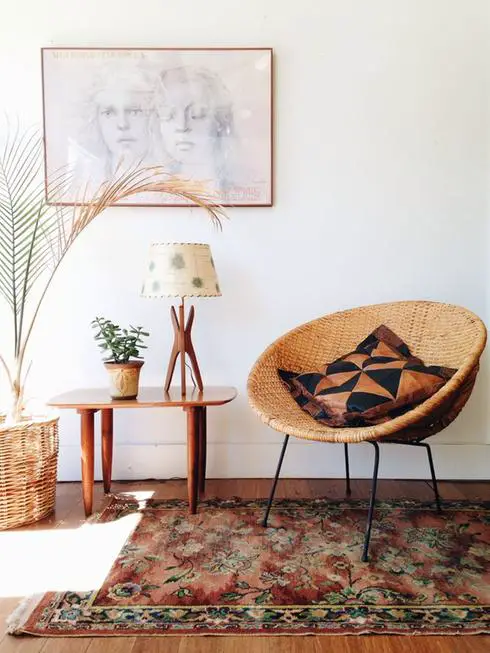 A vintage wicker chair amidst potted plant in a room.