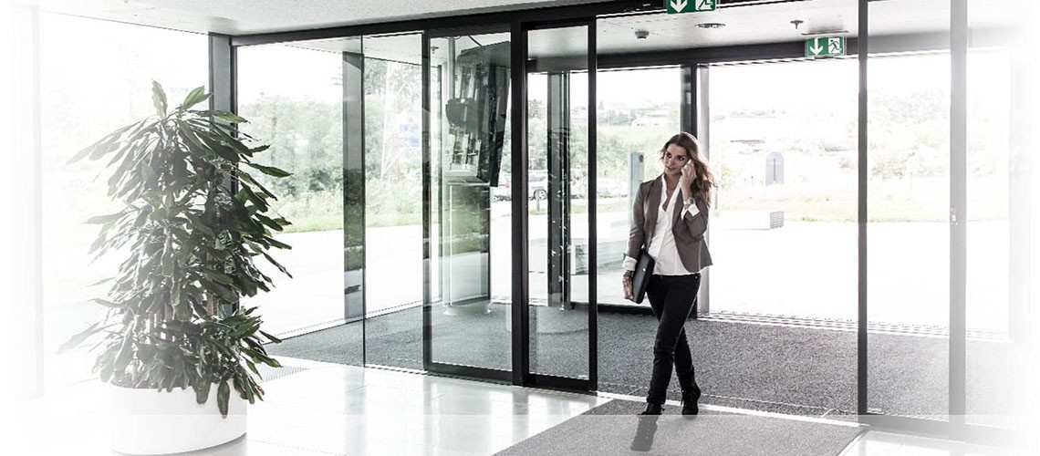 A woman is standing in front of a glass commercial door.