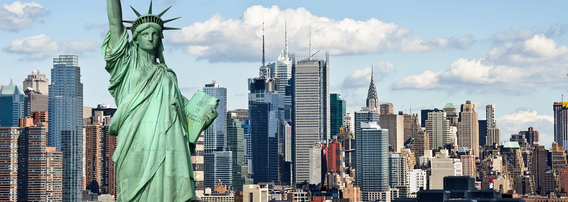 The Statue of Liberty stands in front of a city skyline on a trip to New York.