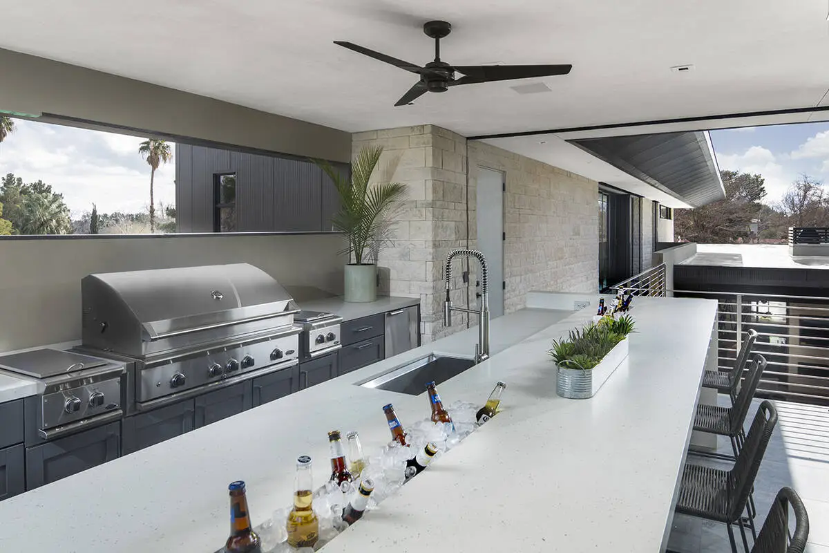 Modern outdoor kitchen with grill and bar seating.