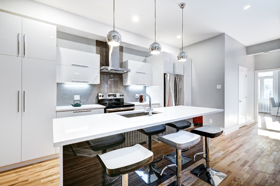 A modern kitchen with white cabinets and bar stools featuring a breakfast bar.