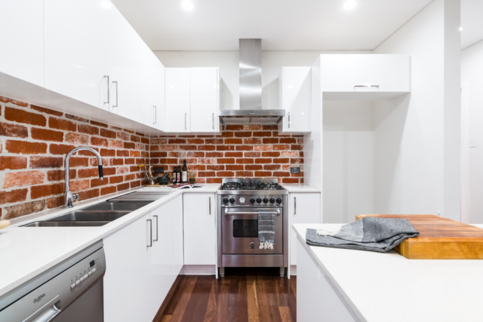 Exposed brick wall in white kitchen