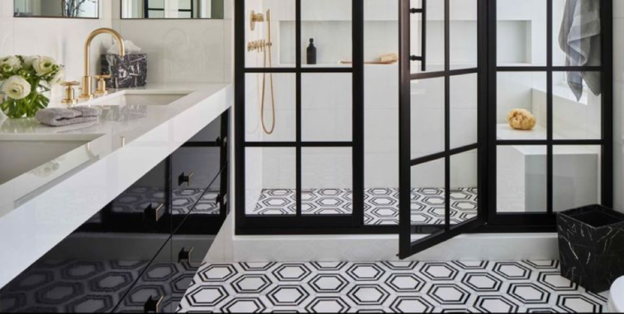 A monochrome bathroom featuring black and white tiles and a glass shower door.