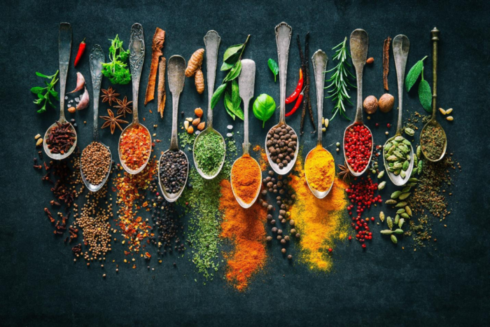 Old spoons and colorful spices on a board.
