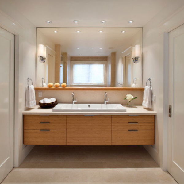 A bathroom with two floating vanities and a mirror.