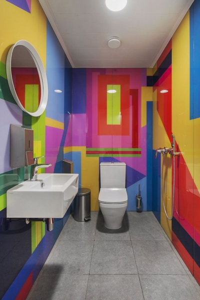 A colorful bathroom with vibrant wallpaper and a toilet and sink.