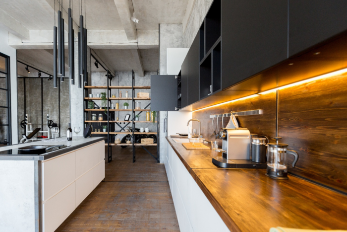 A modern industrial kitchen with a wooden counter top.