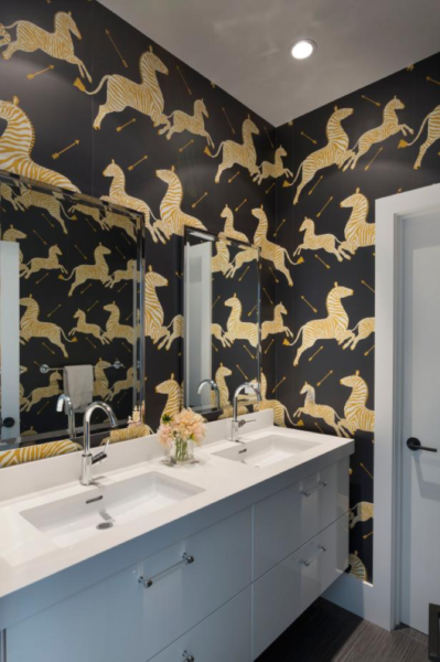 A bathroom with opulent gold and sleek black wallpaper.