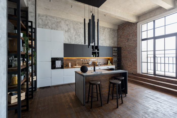 An industrial style kitchen with wooden floors and a large window featured in 10 Industrial Kitchen Designs.