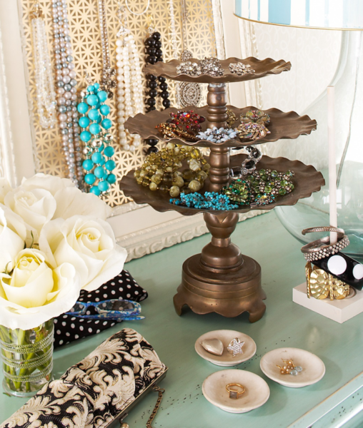 Three tiers of jewelry on a table with additional bathroom storage.