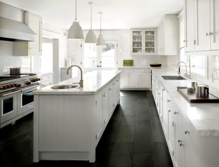 A kitchen with white cabinets and black counter tops, featuring a black and white color scheme.
