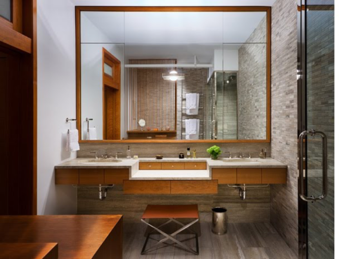 A contemporary bathroom with a wooden vanity and mirror.