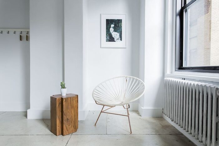 A small space hack - a white chair sits next to a radiator in a room.