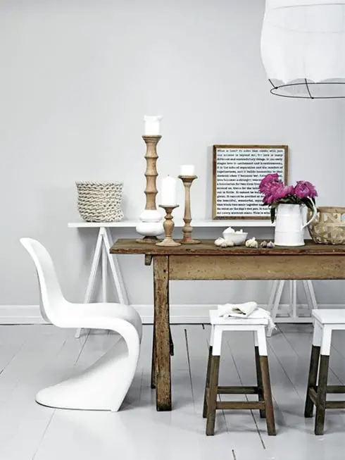 A white dining room with a wooden table and stools, showcasing affordable decor changes.