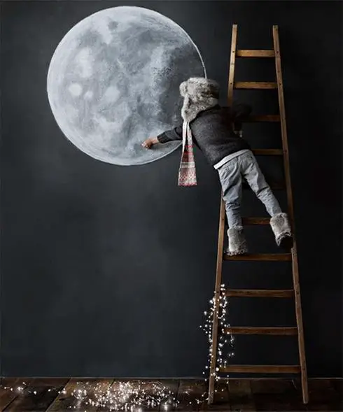 A child standing on a ladder next to a painted moon, showcasing affordable decor options.