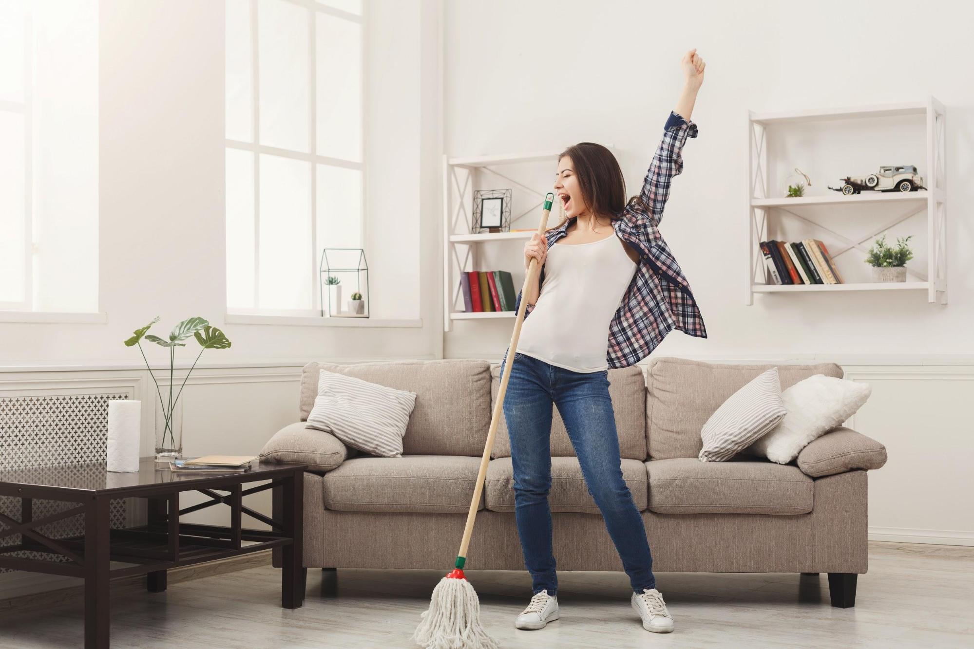 A woman mopping her living room to achieve a fresh home.