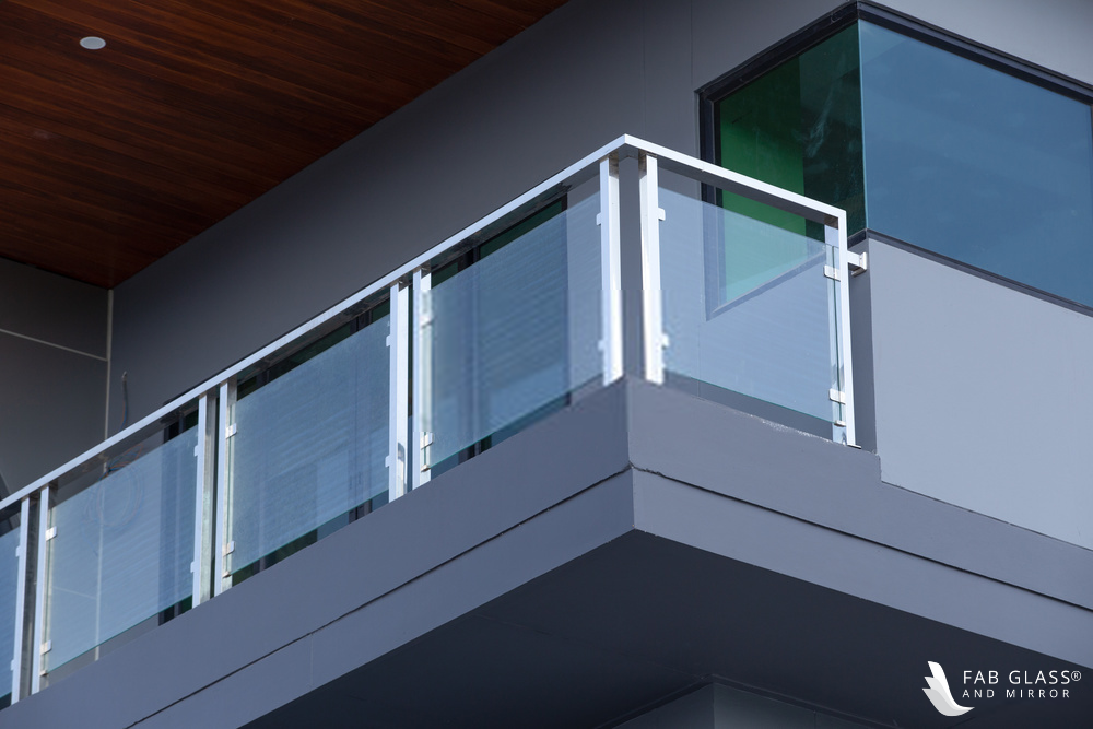 A balcony featuring tempered glass railings on a grey building.