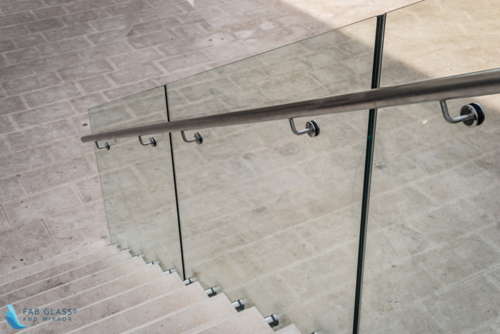 A tempered glass railing with a metal handle.