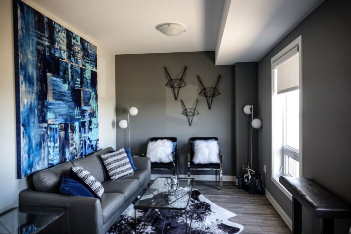 A living room with stylish wall décor ideas, featuring a grey couch and blue wall art.