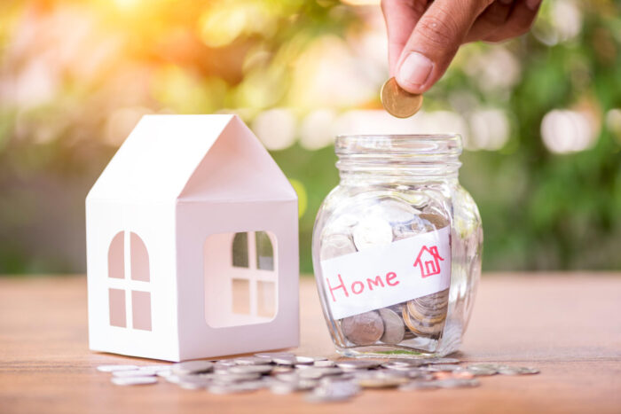 Hand saving money in the glass jar for buying new home