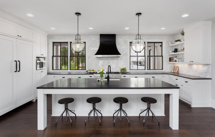 A white kitchen with black counter tops and stools debunks Home Staging Myths.