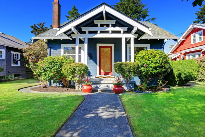 Debunking Home Staging Myths for a blue house with a green lawn and bushes.