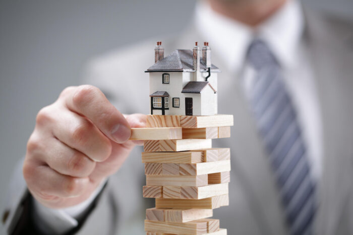 A property sales agent displaying a model house on wooden blocks.