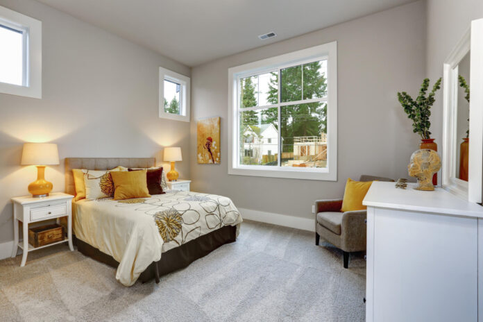 Guest modern bedroom interior with grey walls and orange pillows