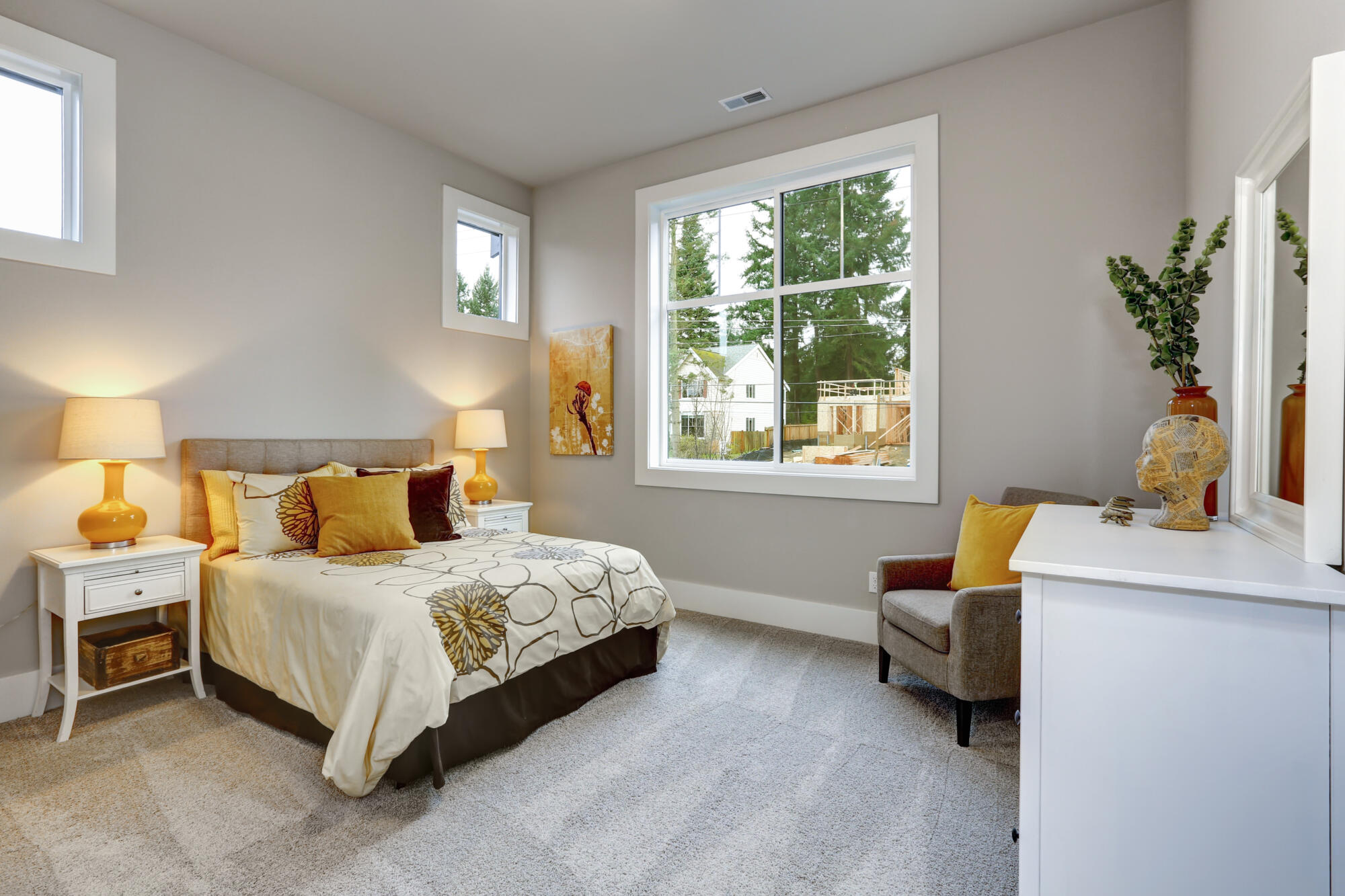 A guest bedroom with a bed, a dresser, and a window.