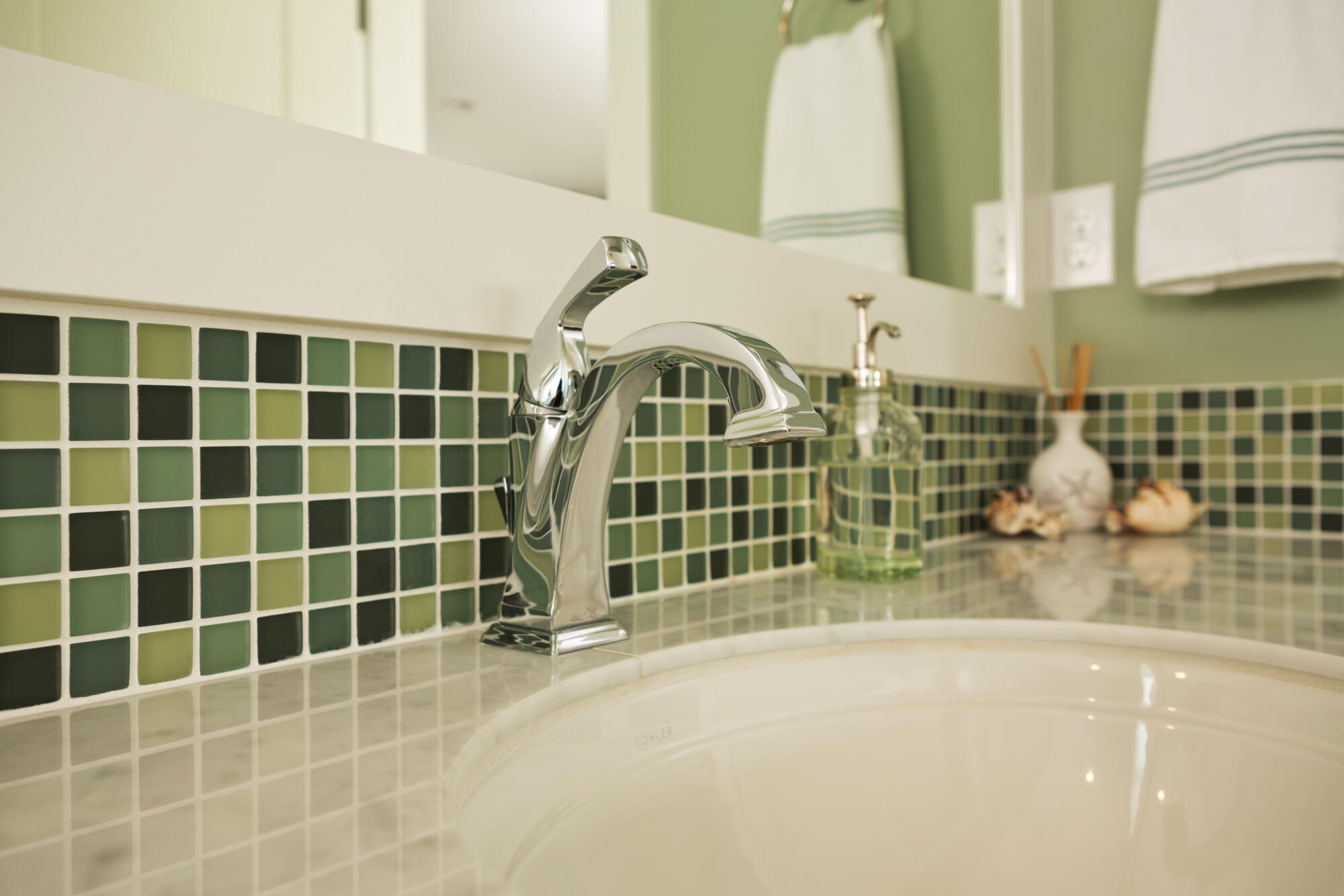 A bathroom with green and white tiled walls.